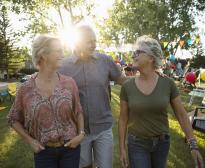 Trois seniors discutent lors d'une fête dans un jardin.