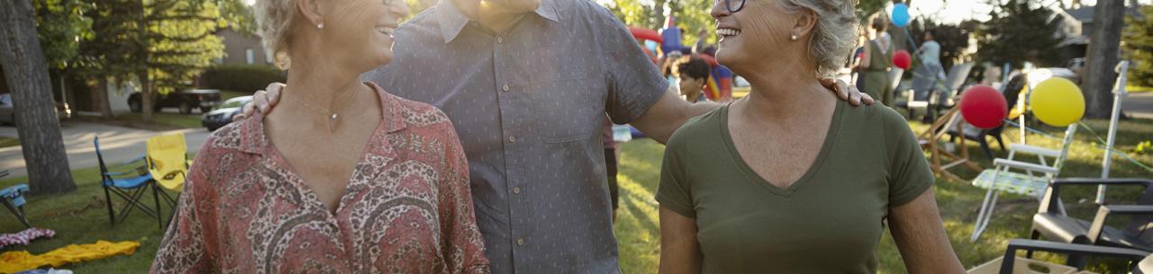 Trois seniors discutent lors d'une fête dans un jardin.