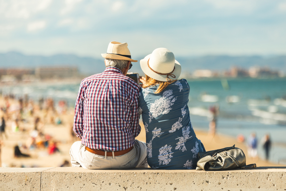 Un couple de cinquantenaire, de dos, se prend en photo tout en regardant la plage 