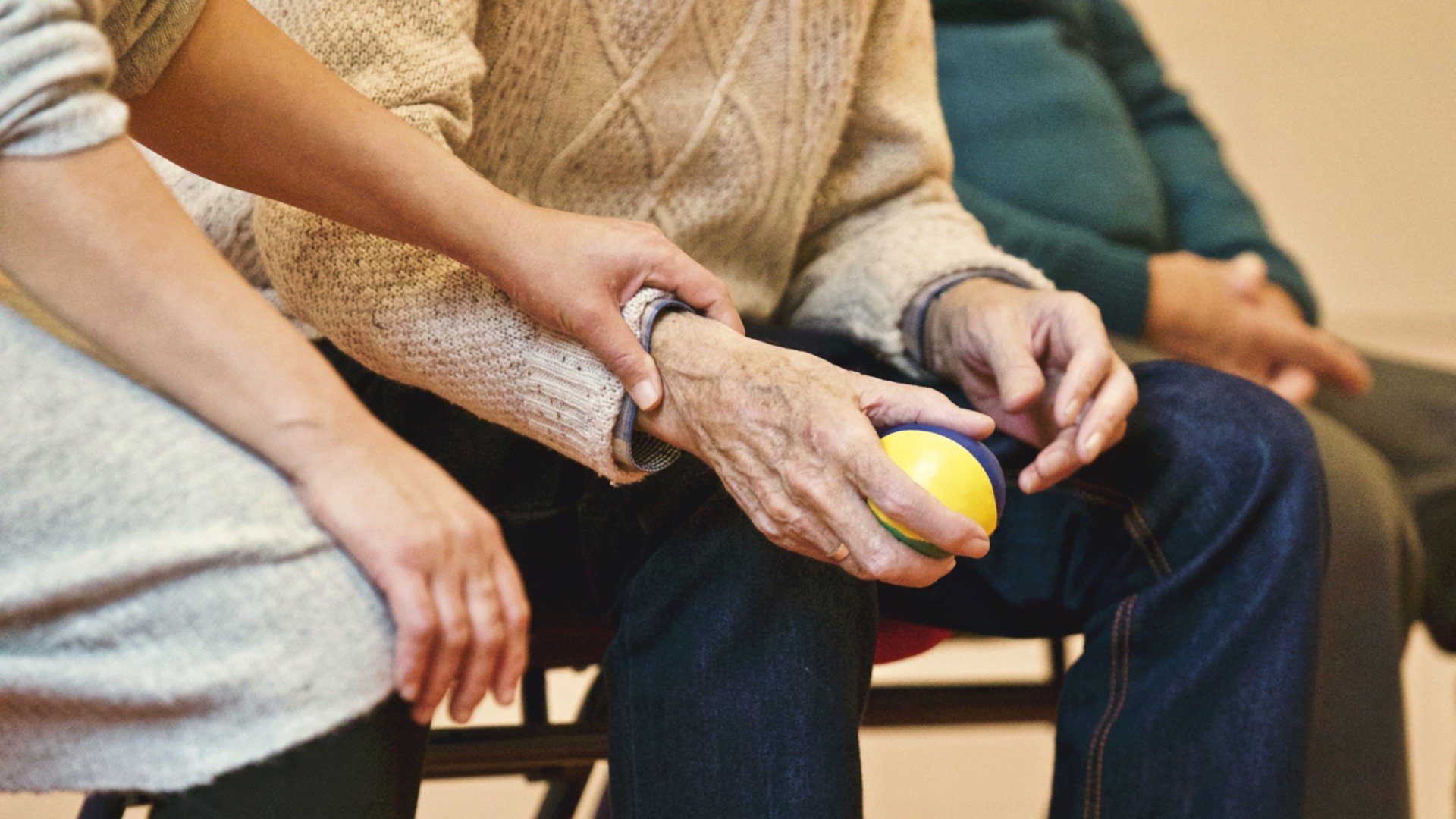 Une aidante tient la main de son père dépendant