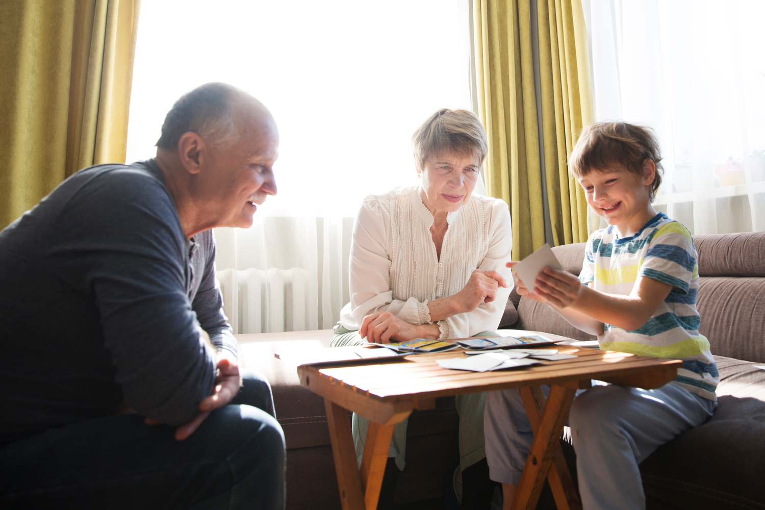 Une famille d'accueil jouent à un jeu de société avec le senior qu'elle héberge