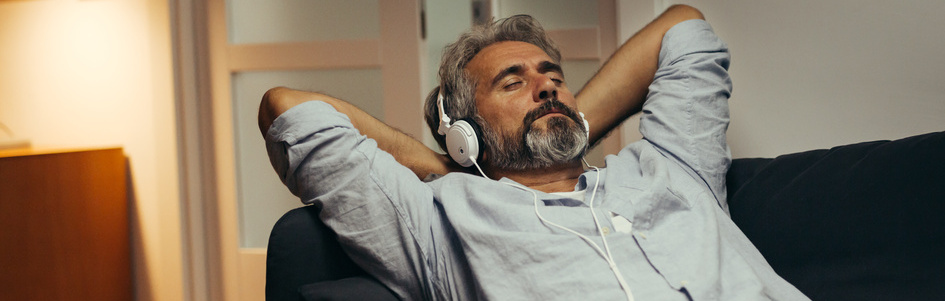 Un homme d'une cinquantaine d'années se relaxe en écoutant de la musique sur son canapé