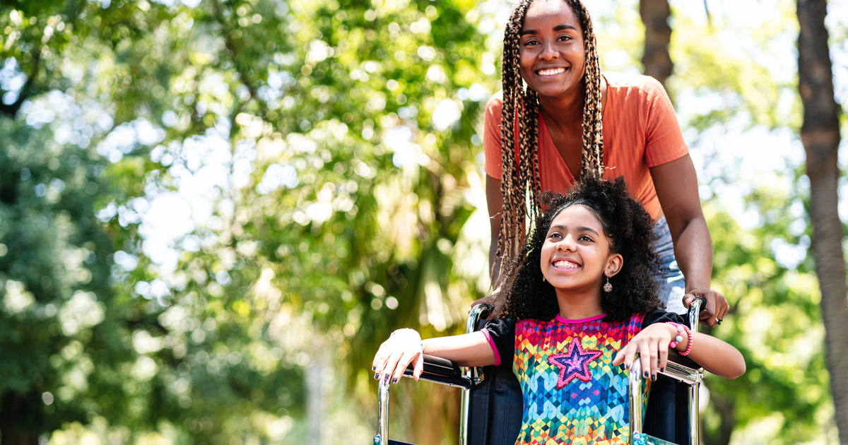 Une mère pousse le fauteuil de sa fille handicapée pendant un séjour de répit