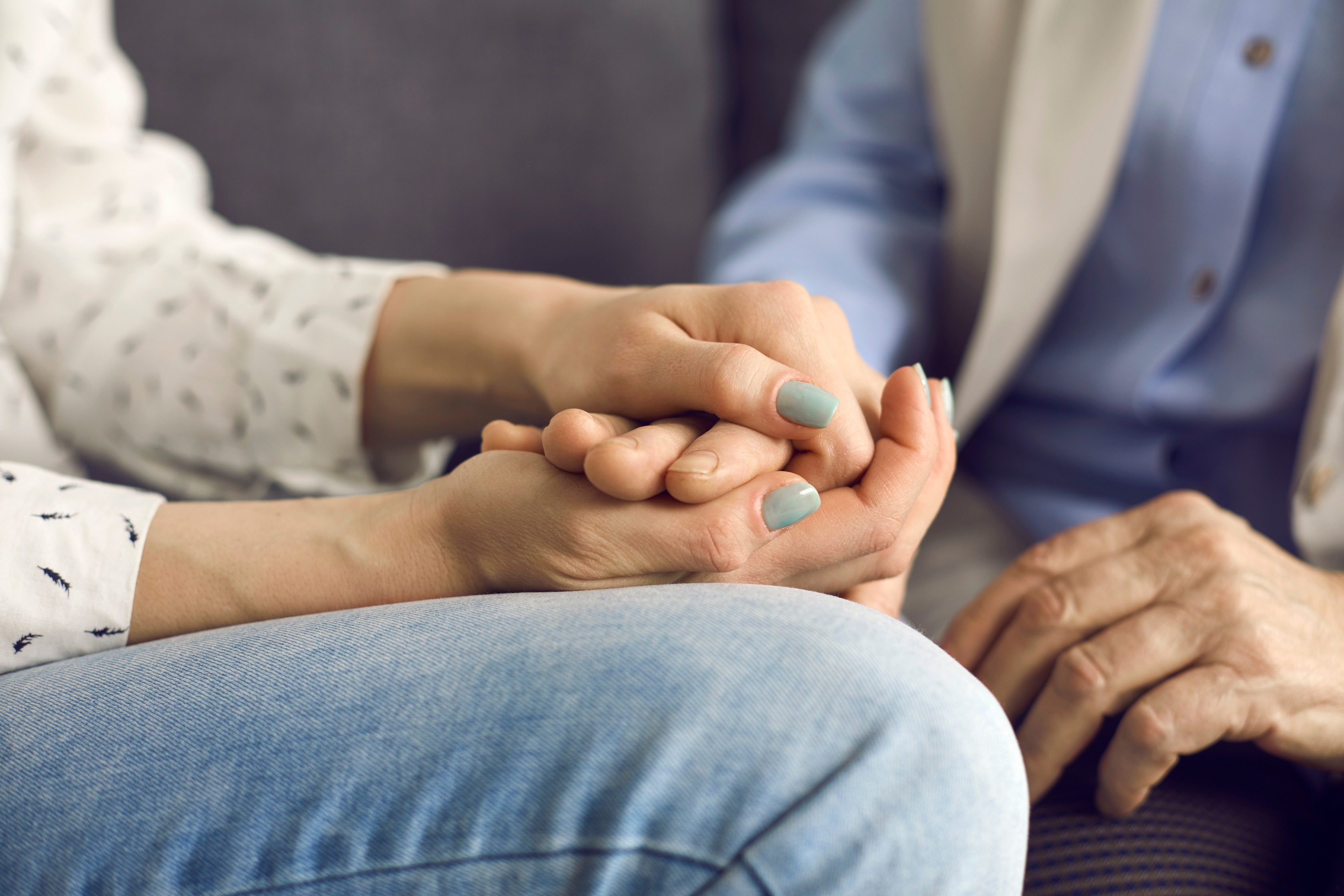 Une femme tient la main de sa mère atteinte d'un cancer