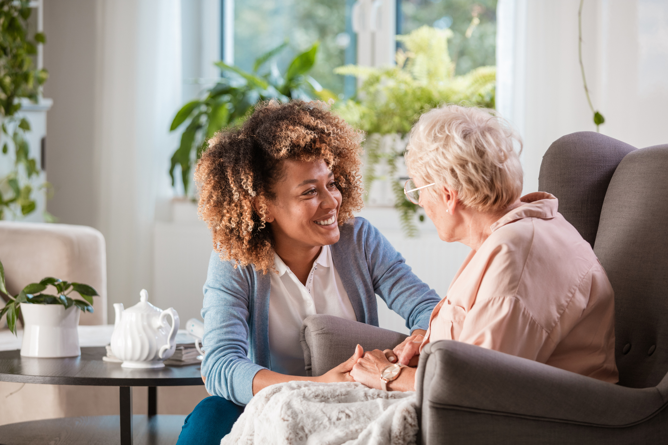 Une femme discute avec une personne âgée autour d'un thé.