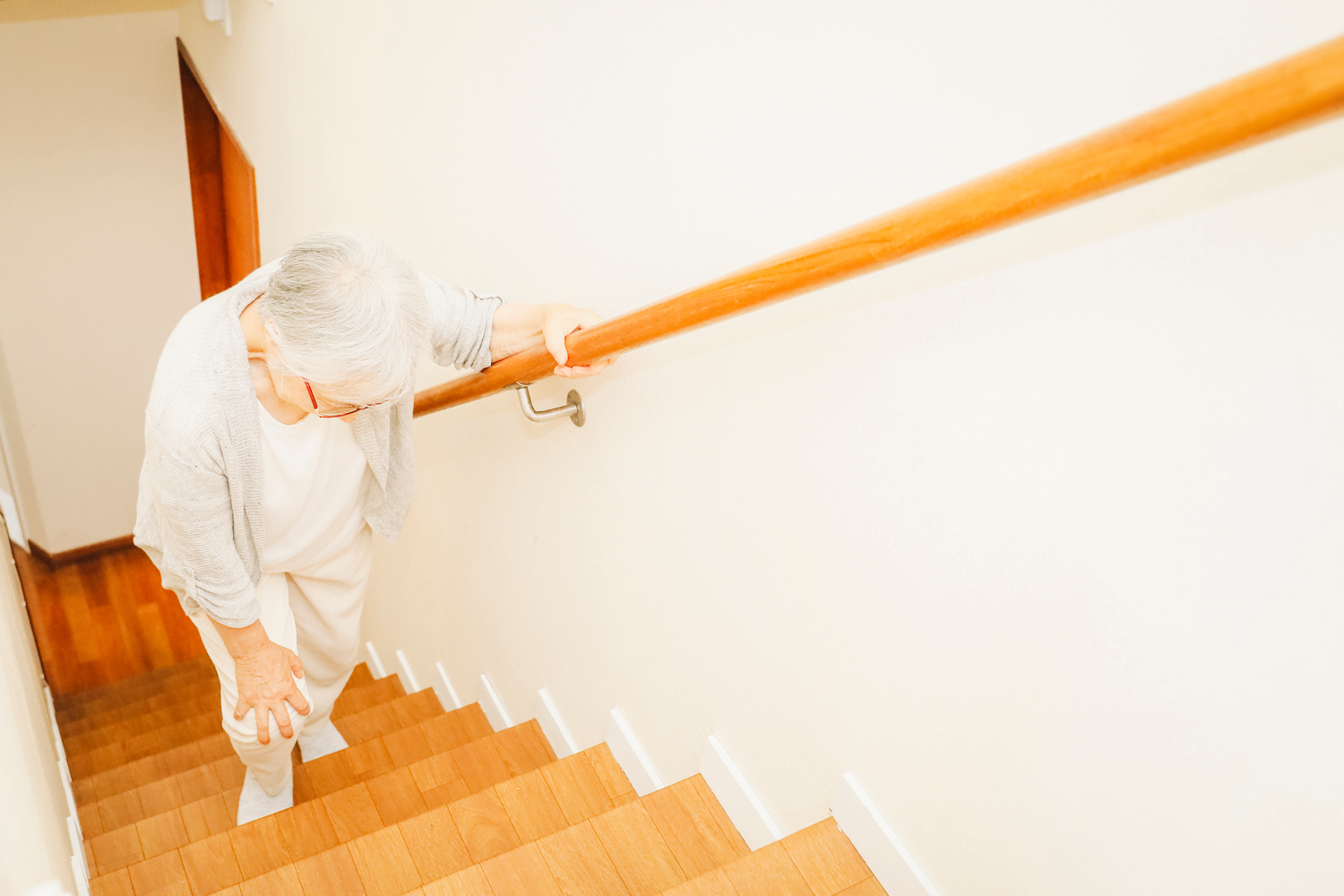 Une senior en difficulté dans les escaliers d'un logement non adapté