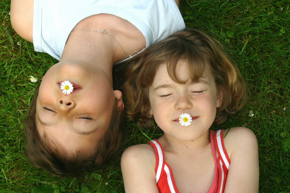 deux petites filles en colonies de vacances inclusives s'amusent allongées dans l'herbe