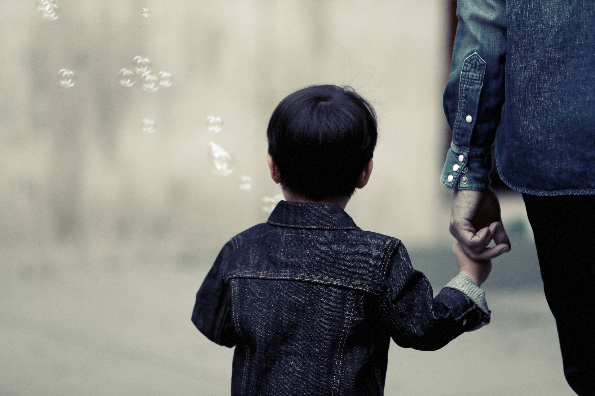 Un enfant en situation de handicap tient la main de son parent.