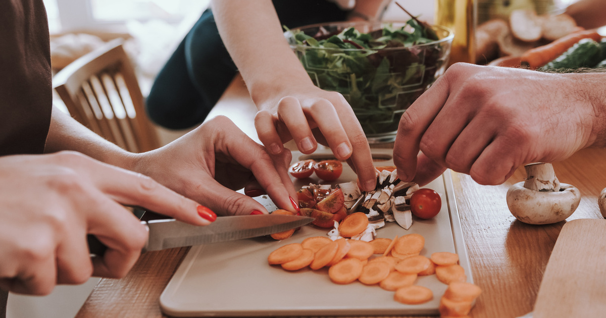 Une famille découpe des légumes en préparant le repas ensemble