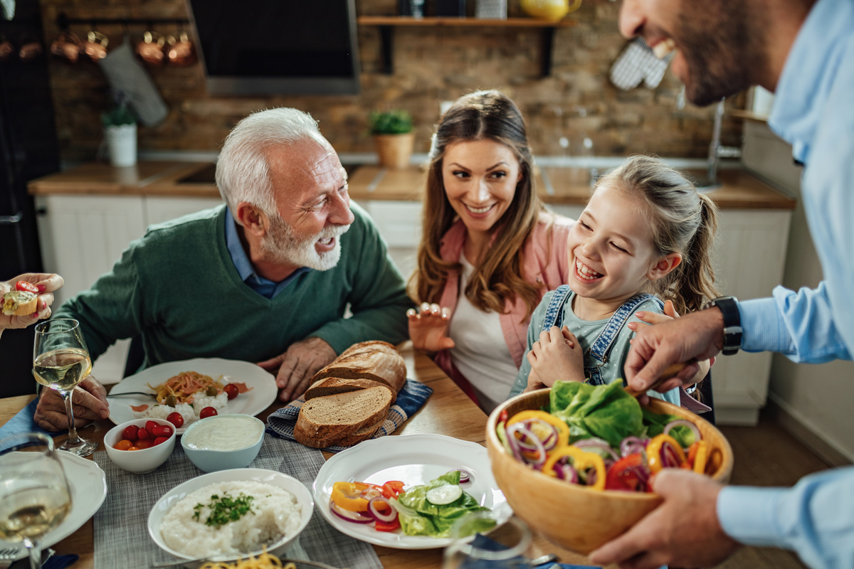 Une famille d'accueil partage le repas avec le senior qu'elle héberge