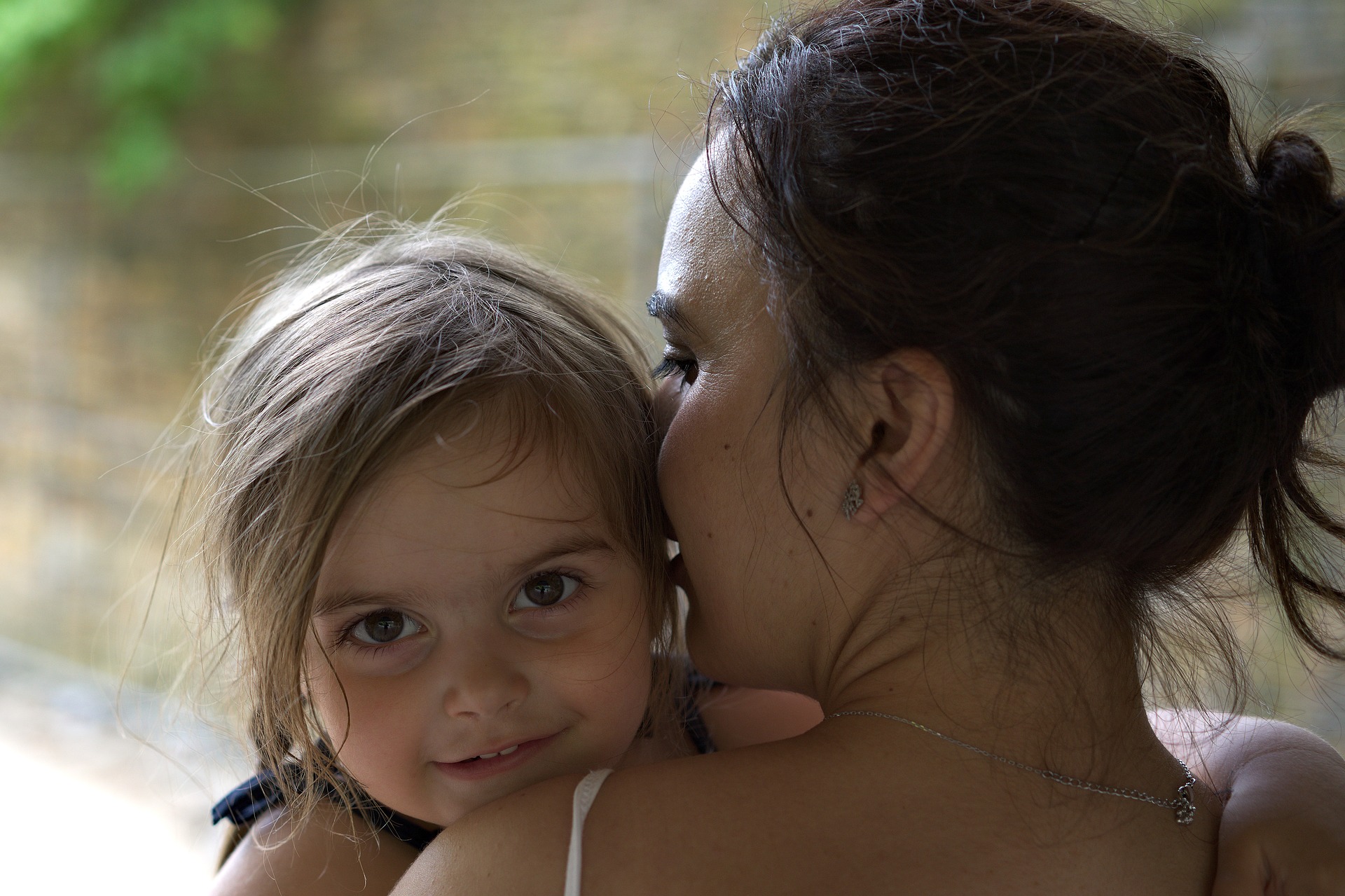 Une maman porte  petite fille handicapée dans ses bras.