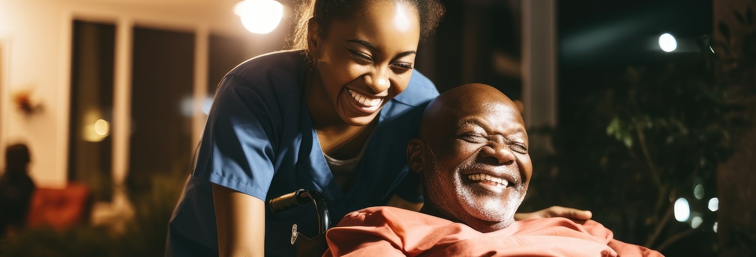 une aide soignante rigole avec un homme âgé dont elle pousse le fauteuil roulant