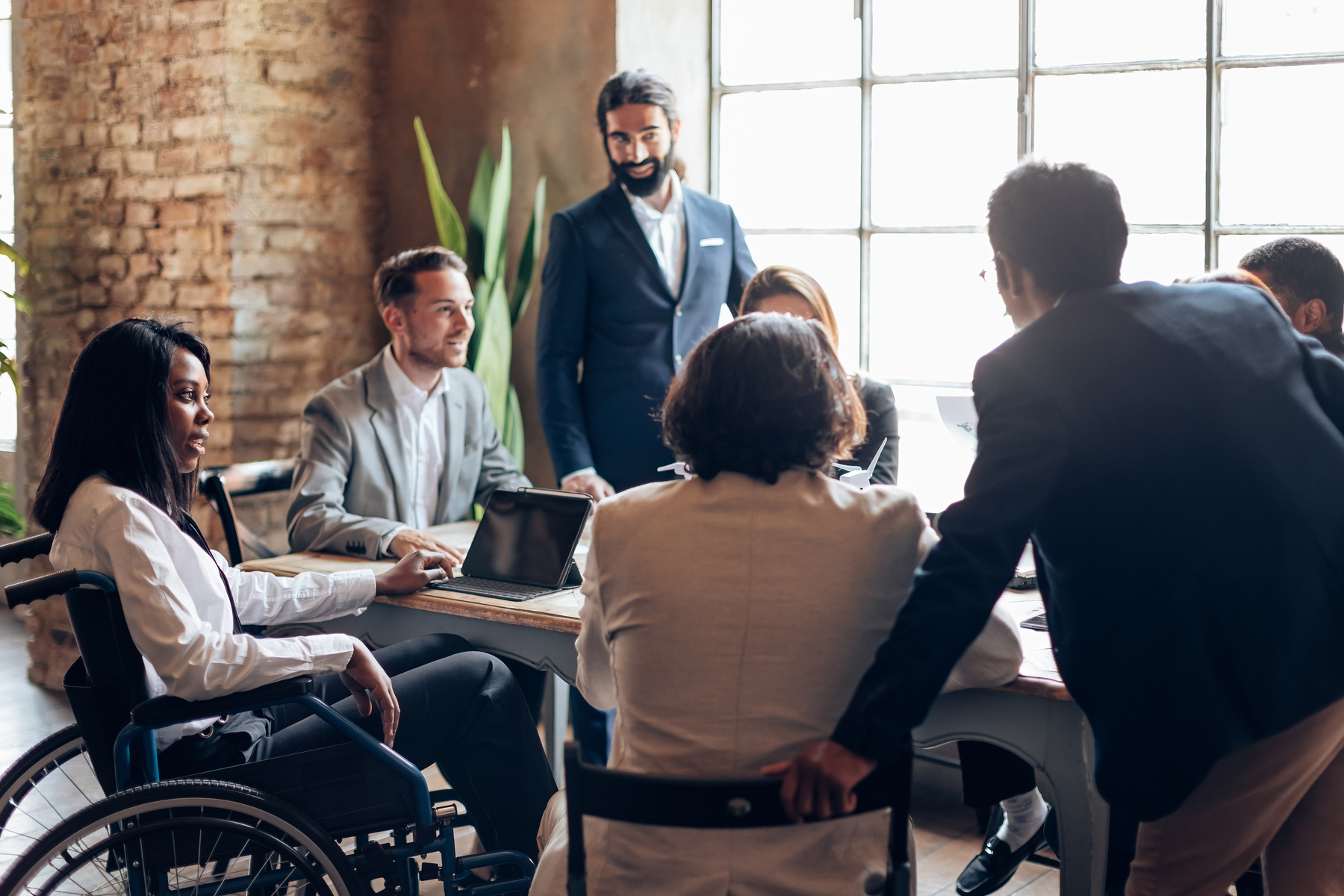 une femme en fauteuil roulant participe à une réunion avec ses autres collègues