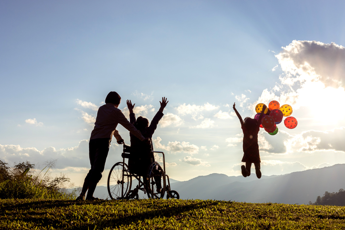 Une mère et ses deux enfants, dont un en fauteuil roulant, observent le lever du soleil